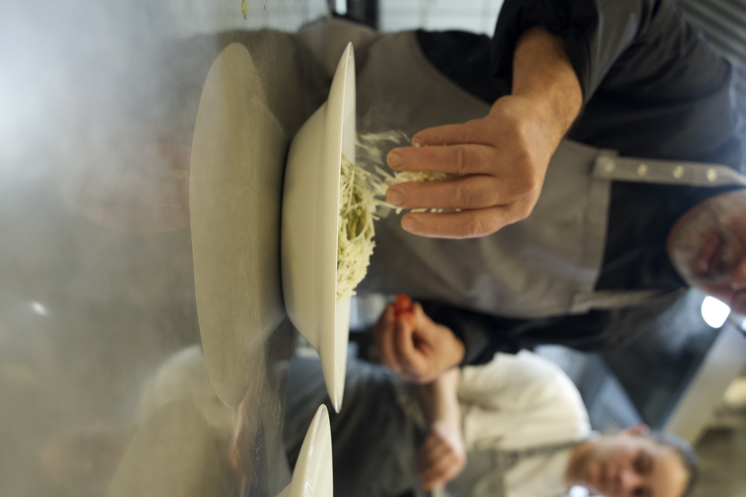 Der Küchenchef streut frischen Käse auf die Pasta — Ristorante da Vinci